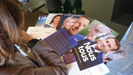 Une femme devant les programmes des candidats à l'élection présidentielle, le 4 avril 2022. (NICOLAS GUYONNET / HANS LUCAS)