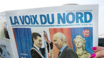 Un lecteur tenant un exemplaire du quotidien régional "La Voix du Nord", en septembre 2014 (photo d'illustration) (DENIS CHARLET / AFP)