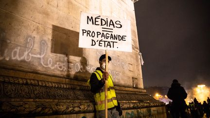 Un "gilet jaune" montre une pancarte contre les médias, le 1er décembre 2018 à Paris. (LAURE BOYER / HANS LUCAS / AFP)