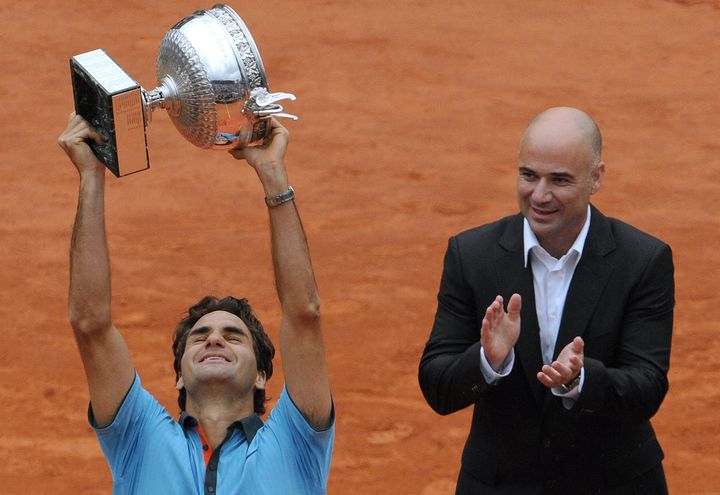 Le Suisse Roger Federer soulève le trophée tant convoité du vainqueur de Roland-Garros, remis par Andre Agassi le 7 juin 2009. (LIONEL BONAVENTURE / AFP)