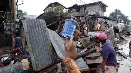 Un habitant transporte sur ses &eacute;paules un bidon d'eau potable au milieu des d&eacute;combres, &agrave; Cagayan de Oro.&nbsp; (DENNIS M. SABANGAN / EPA / MAXPPP)