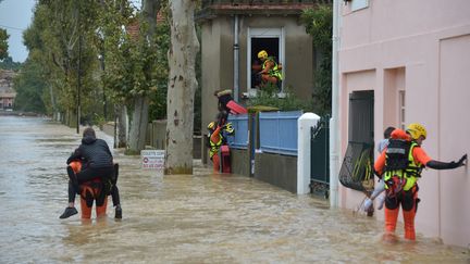 Des pompiers aidant des habitants de Trèbes (Aude) à évacuer, lundi 15 octobre 2018. (PASCAL PAVANI / AFP)