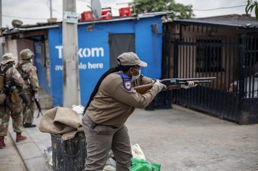 Un policier tire des balles en caoutchouc pour forcer des habitants à rester chez eux, le 31 mars 2020 dans le township d'Alexandra à Johannesburg. (MICHELE SPATARI / AFP)