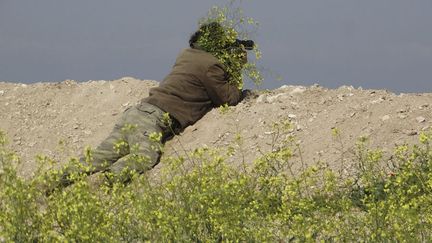 Un soldat rebelle est camoufl&eacute; pour pouvoir observer avec ses jumelles pr&egrave;s de Babolin (Syrie), le 4 avril 2014. (REUTERS)