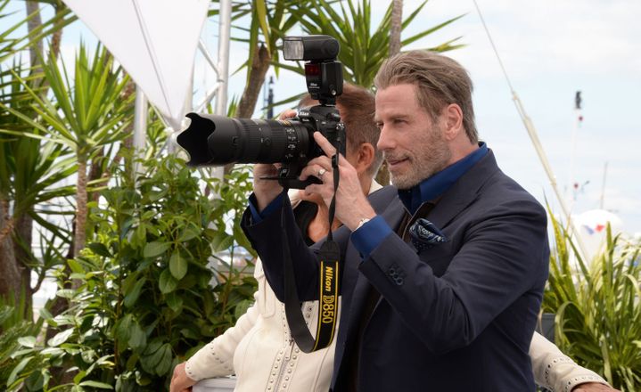 Le comédien John Travolta utilise l'appareil remis par le photographe Marcelo Nlele pour prendre en photo les photographes qui le mitraillent en mai 2018 lors d'un photocall du festival de Cannes.  (Marcelo Nlele/Presscrea)