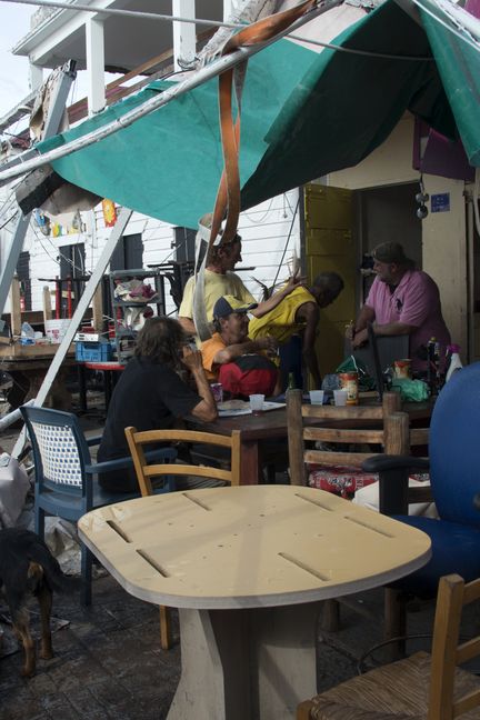 Des habitants du Marigot attablé à la terrasse improvisée d'un bar, le 14 septembre 2017,&nbsp;après le passage de l'ouragan Irma sur l'île de Saint-Martin. (HELENE VALENZUELA / AFP)