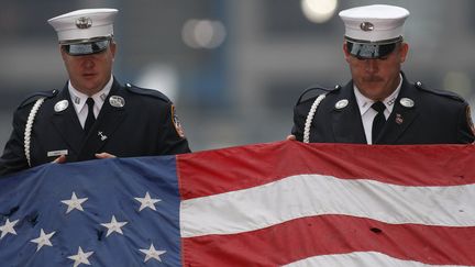 Des pompiers new-yorkais tiennent un drapeau am&eacute;ricain, pendant une c&eacute;r&eacute;monie pour le 6e anniversaire des attentats du 11-Septembre, &agrave; New York, le 11 septembre 2007. (CHIP EAST / REUTERS)