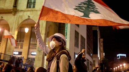 Une manifestante porte le drapeau du Liban, lors d'un rassemblement contre le gouvernement, le 22 janvier 2020. (PATRICK BAZ / AFP)