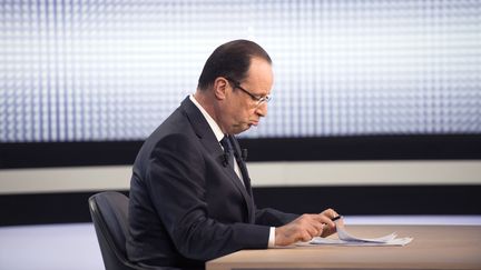 Fran&ccedil;ois Hollande consulte ses notes sur le plateau de France 2, le 28 mars 2013 &agrave; Paris. (FRED DUFOUR / AFP)