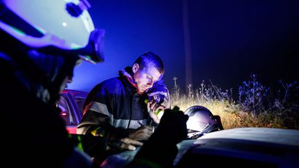 Au c&oelig;ur de la nuit, les pompiers font un point sur leur combat contre les flammes. L'un deux semble remplir une feuille d'intervention &eacute;clair&eacute;e par une lampe torche et la lumi&egrave;re bleue des gyrophares. (THIBAUD MORITZ / MAXPPP)