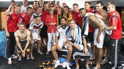 La chanceli&egrave;re allemande, Angela Merkel, entour&eacute;e des joueurs de la Mannschaft, le 16 juin 2014, &agrave; Salvador, au Br&eacute;sil. (GUIDO BERGMANN / DPA)