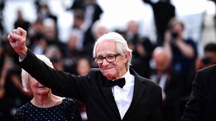 Toujours le point levé, dans ses films comme dans la vie. Ken Loach est arrivé sur le tapis rouge et le silence s'est fait, comme si tout le monde saisissait la scène historique qui était en train de se jouer. Le monstre sacré du cinéma britannique, 86 ans, foule le tapis rouge pour présenter "The Old Oak", film avec lequel il pourrait obtenir une troisième Palme d'or. Ce géant du cinéma social a remporté la distinction en 2006 et 2017 pour "Le vent se lève" et "Moi, Daniel Blake". (LOIC VENANCE / AFP)