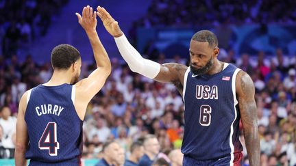 Stephen Curry et LeBron James lors du match des Jeux olympiques entre les Etats-Unis et la Serbie, le 28 juillet 2024 à Villeneuve-d'Ascq (Nord). (LAURENT SANSON / PANORAMIC / DPPI / AFP)