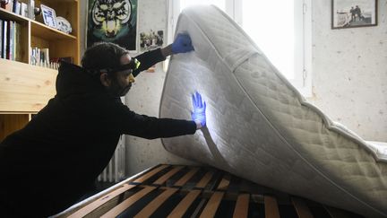 Un homme fouille dans le tissu des matelas pour éliminer les punaises de lit, le 28 octobre 2023, à Paris. (MAGALI COHEN / HANS LUCAS)