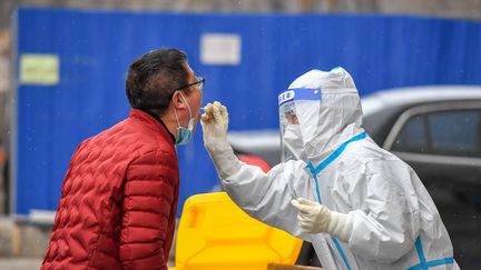 Un soignant teste un homme au Covid-19 à Jilin, en Chine, le 12 mars 2022. (ZHANG NAN / XINHUA / AFP)