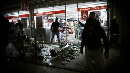 Des gens&nbsp;se tiennent devant un magasin pillé, le 21 juin 2020, à Stuttgart, en Allemagne. (JULIAN RETTIG / DPA)