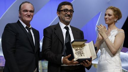 Le r&eacute;alisateur turc Nuri Bilge Ceylan, Palme d'or pour Winter Sleep, entour&eacute; du r&eacute;alisateur&nbsp;Quentin Tarentino et &nbsp;de l'actrice Uma Thurman, &agrave; la c&eacute;r&eacute;monie de cl&ocirc;ture du 67e festival de Cannes, le 24 mai 2014.&nbsp; (VALERY HACHE / AFP)