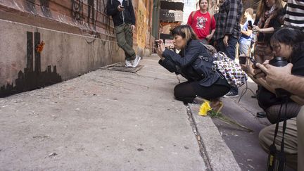 Des passants photographient la derni&egrave;re oeuvre du street-artist Banksy &agrave; New York (Etats-Unis), le 15 octobre 2013. (FRANCES M. ROBERTS / NEWSCOM / SIPA)