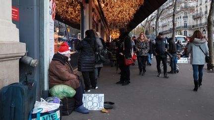 Un SDF fait la manche devant une vitrine d'un grand magasin à Paris. (MAXPPP)