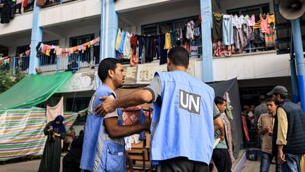 Des travailleurs de l'UNRWA devant une école de Khan Younès, au sud de Gaza, transformée en refuge pour les déplacés, qui se massent au sud de l'enclave pour échapper au feu israélien. (MAHMUD HAMS / AFP)