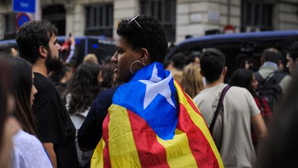 Une femme enveloppée dans le drapeau indépendantiste catalan, au lendemain du référendum interdit par le gouvernement espagnol, à Barcelone, le 2 octobre 2017. (JOAN CROS / NURPHOTO / AFP)