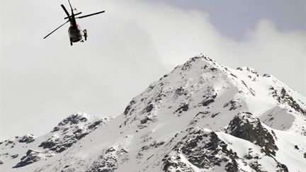 Un hélicoptère de recherches au dessus du village suisse de Bourg-Saint-Pierre, après une avalanche, le 23 mars 2011 (AFP/FABRICE COFFRINI)