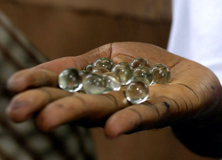 En Gambie, un homme montre les billes utilisées pour l'élection présidentielle dans un bureau de vote à Serrekunda le 22 septembre 2006.  (SEYLLOU DIALLO / AFP)