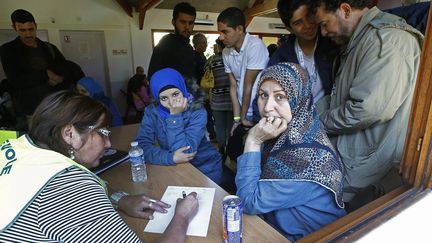 Des r&eacute;fugi&eacute;es s'enregistrent aupr&egrave;s des b&eacute;n&eacute;voles du Secours populaire, &agrave; leur arriv&eacute;e au centre d'accueil de Cergy-Pontoise (Val d'Oise), le 9 septembre 2015. (JACKY NAEGELEN / REUTERS)