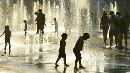 Des enfants jouent dans une fontaine place des Arts à Montréal, le 3 juillet 2018. (EVA HAMBACH / AFP)