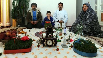 Une famille afghane assise autour de son Haft Sîn, table traditionnelle où sont dressés sept objets symboliques dont le nom commence par S.
	Sept, chiffre cité dans le livre de Zarathoustra (prophète, fondateur du zoroastrisme, ancienne religion de la Perse), est un nombre porte-bonheur.
	  (AFP PHOTO / Aref KARIMI)