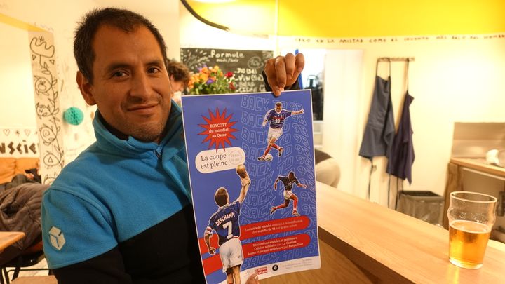 Au bar La Cantina, à Paris, Tovar Palacius Miguel présente l'affiche de boycott de la Coupe du monde au Qatar, le 30 novembre 2022 lors du match France-Tunisie. (Louise Le Borgne)