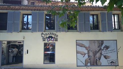 Publicité sur la devanture d'un barbier à Aix-en-Provence, le 10 juillet 2018. (EMILIE BRIFFOD / RADIOFRANCE)