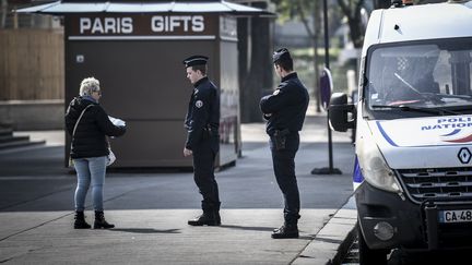 Des policiers contrôlent l'attestation de déplacement d'une passante à Paris, le 28 mars 2020.&nbsp; (STEPHANE DE SAKUTIN / AFP)