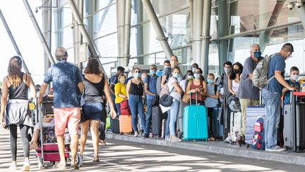 Des passagers font la queue devant l'aéroport Félix-Eboué, à Cayenne (Guyane), le 10 juillet 2020. (JODY AMIET / AFP)