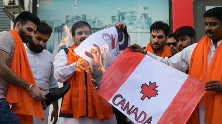 Des activistes indiens brûlent un drapeau canadien et un portrait de Justin Trudeau, le 23 septembre 2023. (NARINDER NANU / AFP)