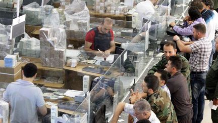 Des Syriens attendent à la banque le versement de leurs salaires après l'injection, le 30 juin 2015, de nouveaux billets de 1000 livres par la Banque centrale de Syrie. (AFP PHOTO/ Louaï Beshara)