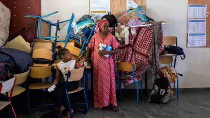 Deux personnes reçoivent de l'aide alimentaire après le passage du cyclone Chido à Mayotte, le 29 décembre 2024 à Mamoudzou. (PATRICK MEINHARDT / AFP)