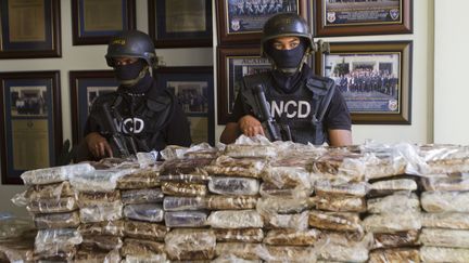 Des policiers dominicains posent devant les 680 kg de coca&iuml;ne saisie &agrave; bord du Falcon 50 des quatre Fran&ccedil;ais, le 21 mars 2013. (ERIKA SANTELICES / AFP)