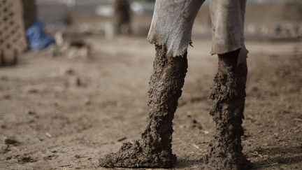 Les jambes recouvertes de boue d'un ouvrier dans une fabrique de briques &agrave; Sanaa (Yemen), le 26 juin 2012. (HANI MOHAMMED / AP / SIPA)