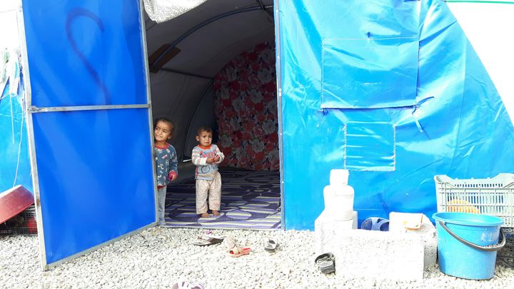 Deux enfants réfugiés avec leurs familles dans une tente bleue des Nations unies, dans le camp de Dibaga, au sud de Mossoul. (MATHILDE LEMAIRE / RADIO FRANCE)