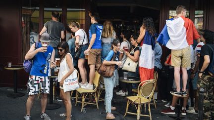 Des supporters tricolores sur la terrasse d'un bar à Paris le 15 juin 2018, durant la finale du Mondial entre la France et la Croatie. (LUCAS BARIOULET / AFP)