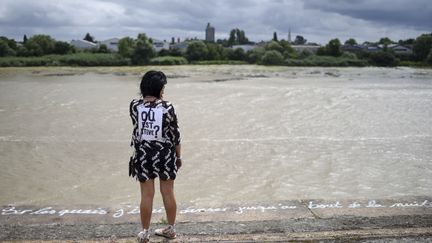 Une femme sur les quais de la Loire, avec une affiche "Où est Steve ?" dans le dos, le 20 juillet 2019 à Nantes. (SEBASTIEN SALOM-GOMIS / AFP)