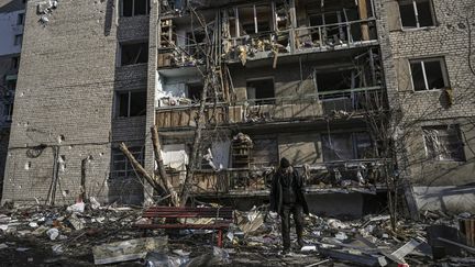 Un&nbsp;civil devant un immeuble d'habitation détruit par des bombardements à Kharkiv, en Ukraine, le 25 mars 2022. (ARIS MESSINIS / AFP)