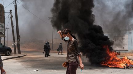 Une femme passe devant un incendie durant des manifestations à Dakar, au Sénégal, le 1er juin 2023. (GUY PETERSON / AFP)