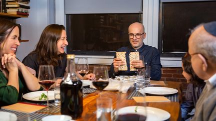 Une famille juive américaine célèbre ensemble la Pâque. Le leader du Seder brise le pain azyme (photo d'illustration, le 04 mars 2022) (HALBERGMAN / E+)