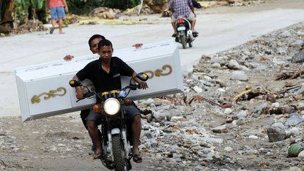 Des employ&eacute;s de pompes fun&egrave;bres transportent un cercueil sur une route endommag&eacute;e par le s&eacute;isme &agrave; La Libertad (Philippines), le 9 f&eacute;vrier 2012. (TED ALJIBE / AFP)