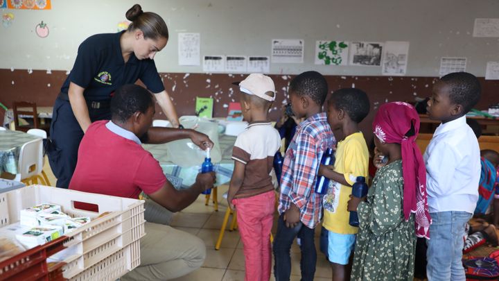 Des enfants reçoivent de l'eau potable dans une école de Longoni, à Mayotte, le 11 octobre 2023. (ROBIN PRUDENT / FRANCEINFO)