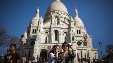 Des touristes prennent un selfie devant le Sacré-Cœur, à Paris, le 30 mars 2017. (Photo d'illustration) (LIONEL BONAVENTURE / AFP)