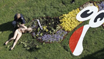 Une f&eacute;ministe du mouvement Femen est arr&ecirc;t&eacute;e par un policier devant la mascotte fleurie de l'Euro, &agrave; Kiev (Ukraine), le 31 mai 2012. (GLEB GARANICH / REUTERS)