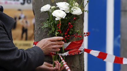 Une femme accroche un bouquet de fleurs sur le site d'une des fusillades, le 14 novembre 2015, à Paris.&nbsp; (GONZALO FUENTES / REUTERS)